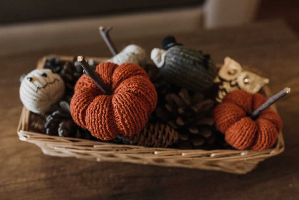 A rectangular wicker basket with crochet pumpkins, acorns and fall decorations.